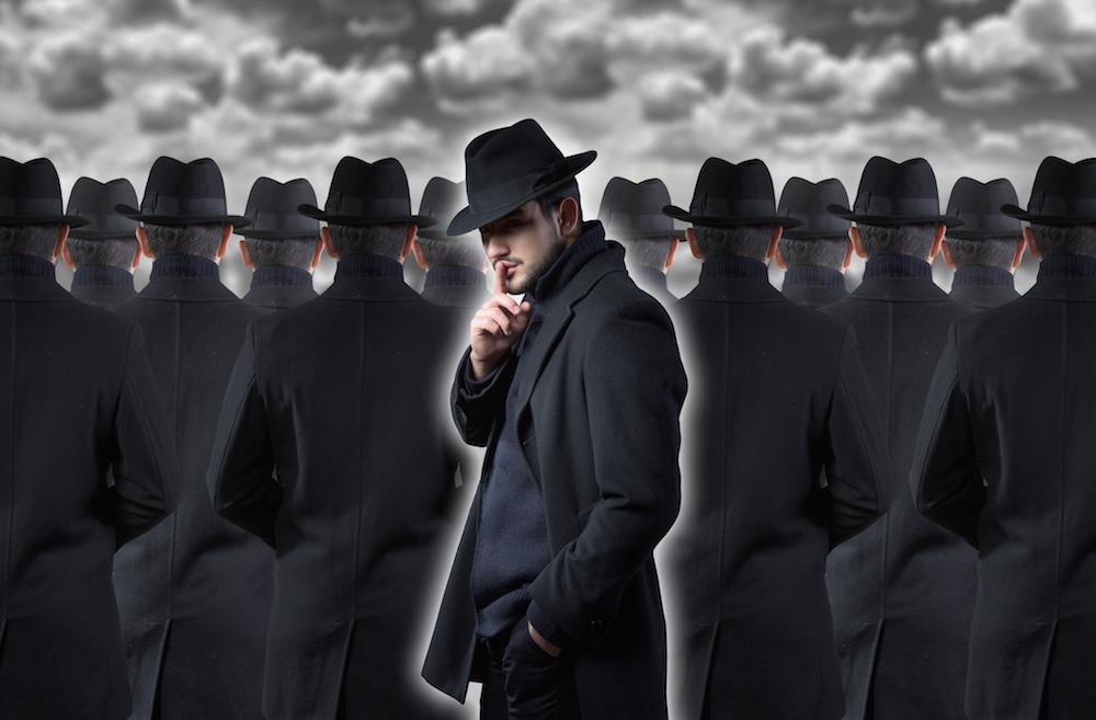 Breaking into a Group image - Men in black hats and coats from back, one turned around doing "sssh" gesture